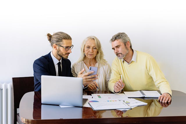 a woman and two men looking at a phone